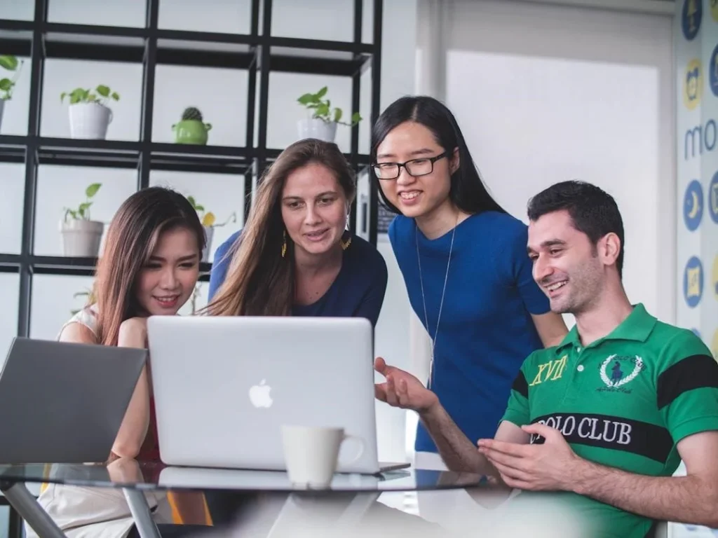 Group of professionals collaborating on AI knowledge management solutions around a laptop